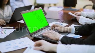 商务会议、会议上，商务人员在带绿色屏幕的笔记本电脑上工作
